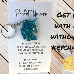 May include: A teal blue glitter unicorn keychain with the text "Pocket Unicorn" and "Get it with or without a keychain!"  The text also reads "Keep this close by so that you'll always know, that you will bring magic everywhere that you go! Never forget all that you can achieve, if you hold this tightly & just believe!" and "Mark Your Worth Creations".