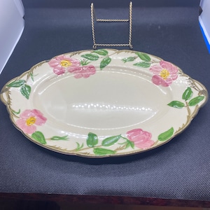 May include: A white oval serving platter with a floral design featuring pink roses and green leaves. The platter has a scalloped edge and two handles.