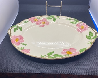 May include: A white oval serving platter with a green vine and pink rose pattern. The platter has two handles on the sides.