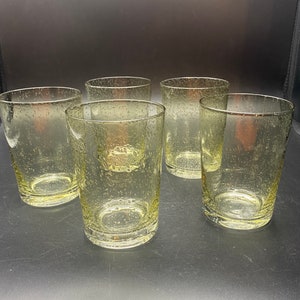 Puede incluir: Conjunto de cinco vasos transparentes de vidrio con una superficie texturizada y burbujeante. Los vasos son todos del mismo tama&ntilde;o y forma.