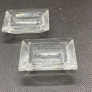 May include: Two clear glass square-shaped dishes with slightly raised edges.