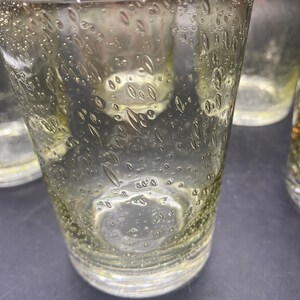 Puede incluir: Juego de cuatro vasos transparentes de vidrio con un dise&ntilde;o texturizado de burbujas. Los vasos tienen un tono ligeramente amarillento.