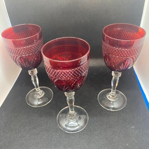 May include: Three red wine glasses with a clear glass stem and base. The glasses have a diamond pattern etched into the glass.