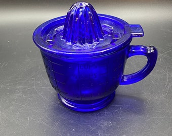 May include: A cobalt blue glass citrus juicer with a built-in measuring cup and a handle. The juicer has a ridged top for squeezing citrus fruits.