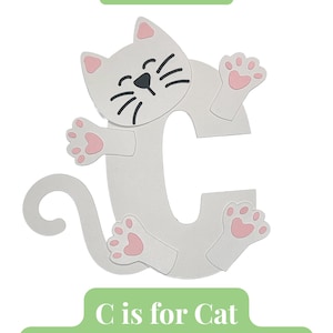 Op de afbeelding: Een lichtgrijze letter C in de vorm van een kat met roze pootkussentjes en oren, zwarte snorharen en ogen. De tekst luidt: Includes all pre-cut pieces needed (Glue not included) en C is for Cat Alphabet Letter Craft.