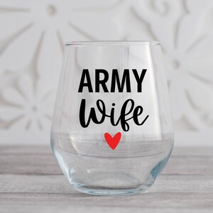 May include: Clear glass wine glass with the text "ARMY wife" in black lettering and a small red heart.