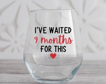 May include: Clear glass wine glass with the text "I've waited 9 months for this" in black lettering and a red heart.