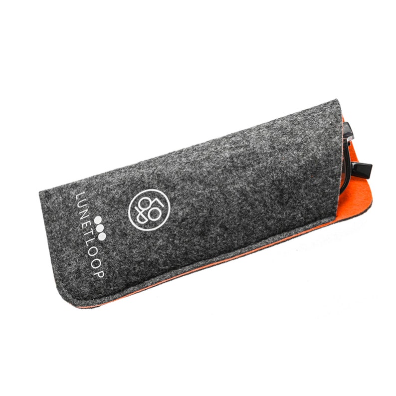 May include: A charcoal gray felt glasses case with a bright orange interior lining. The exterior features the white printed text LUNETLOOP and a circular logo containing a stylized graphic. A pair of black eyeglasses is partially visible inside.