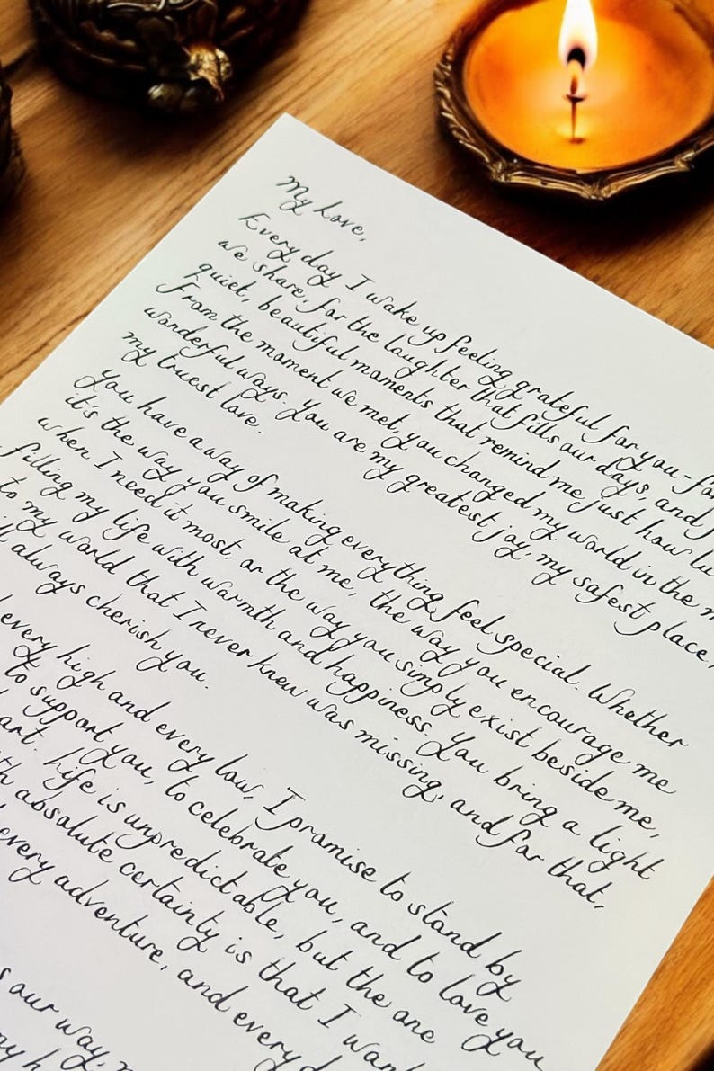 May include: A handwritten love letter with black ink on white paper. The letter expresses gratitude for the recipient's presence and love. The letter is framed and sitting on a wooden surface with a lit candle.