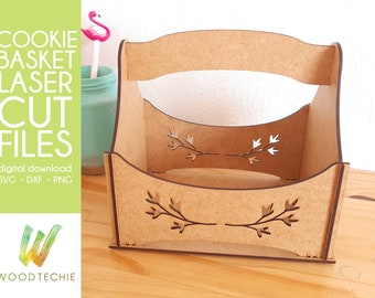 May include: A wooden cookie basket with a cutout design of branches and leaves. The basket has a handle and is made for laser cutting.