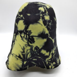 Peut inclure: Un chapeau cloche tie-dye noir et jaune. Le chapeau a une couronne arrondie et un bord légèrement évasé. Le motif tie-dye présente un mélange de couleurs noir et jaune. Le chapeau est en matière souple.