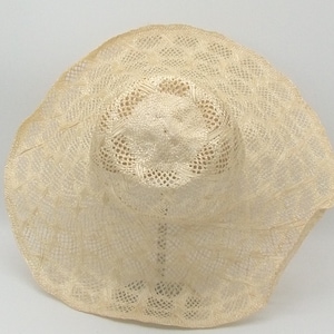 May include: A wide-brimmed straw hat with a delicate, open-weave design. The hat is cream-coloured and has a slightly floppy brim.