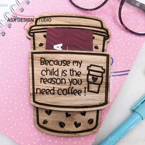 May include: Wooden coffee cup gift card holder with the text "Because my child is the reason you need coffee!" engraved on it. The holder is made of light brown wood and has a cutout of a coffee cup with a heart on it.