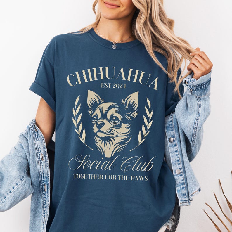 May include: A navy blue t-shirt with a white graphic of a chihuahua dog. The graphic includes the text "Chihuahua Est 2024 Social Club Together for the Paws".