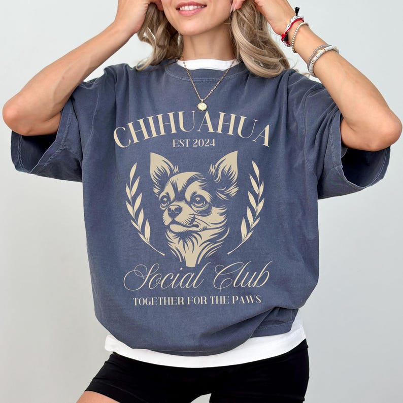 May include: A navy blue t-shirt with a graphic of a chihuahua and the text "Chihuahua Est 2024 Social Club Together for the Paws".