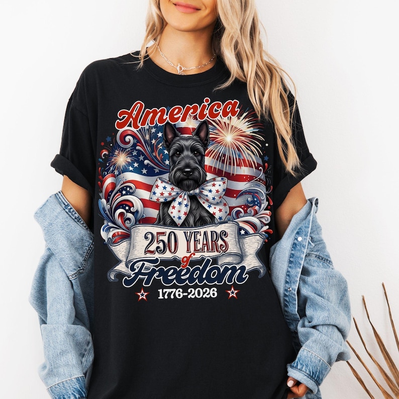 May include: Black t-shirt featuring a patriotic design with a Scottish Terrier dog wearing a bow. The graphic includes the word "America", an American flag, fireworks, and the text "250 Years of Freedom 1776-2026".