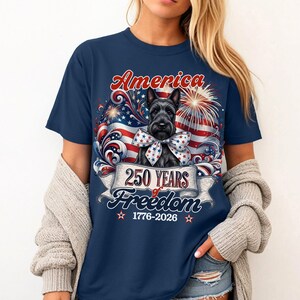 May include: Navy blue t-shirt featuring a Scottish Terrier with a patriotic bow tie, the word "America" in red script, and a banner reading "250 Years of Freedom 1776-2026" with fireworks and an American flag design.