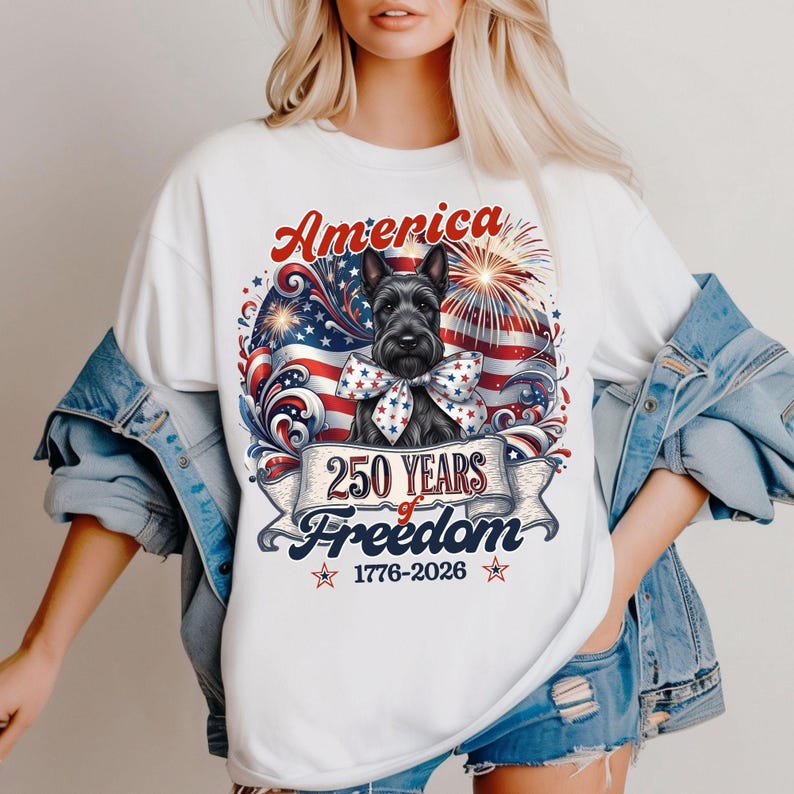 May include: White t-shirt featuring a patriotic design with a black Scottish Terrier wearing a bow tie. The design includes the word "America", fireworks, and a banner that reads "250 Years of Freedom 1776-2026".