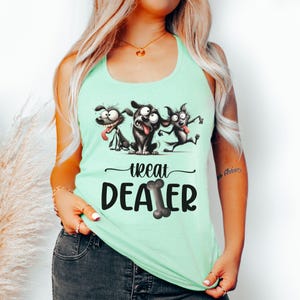 May include: A light green tank top featuring a playful graphic of three cartoon dogs with exaggerated expressions. The text "treat dealer" is printed below the dogs, with the word "dealer" incorporating a bone design.