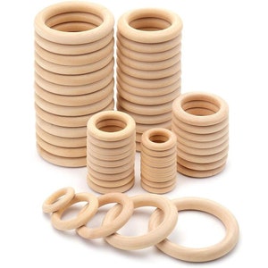 May include: A set of wooden rings in various sizes, stacked and arranged on a white background. The rings are made of natural wood and have a smooth, unfinished surface.