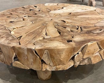 May include: A round, natural wood coffee table with a unique, organic design. The table top is made of many pieces of wood that have been joined together to create a beautiful, rustic look. The table has a natural wood finish and is supported by four sturdy legs.