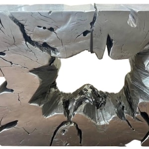 May include: A silver-colored, organically shaped console table. The table has a unique design with a large opening in the center. The surface has a textured, weathered appearance with visible cracks, adding to its rustic charm.