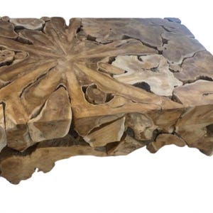 May include: A large, rustic coffee table made from a single piece of reclaimed wood. The wood has a natural, organic shape with a unique grain pattern. The table is perfect for adding a touch of nature to any living room.