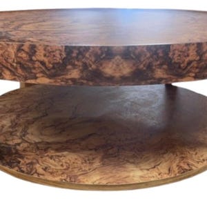 May include: A round coffee table with a two-tiered design. The top and lower shelf feature a brown, patterned surface, supported by light-colored wooden legs. The table is approximately 36 inches in diameter and 18 inches tall.