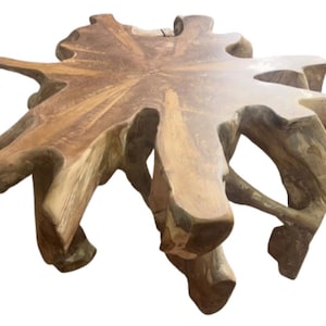 May include: A large, natural wood coffee table with a unique, irregular shape. The table is made from a single piece of wood with a natural, rustic finish.