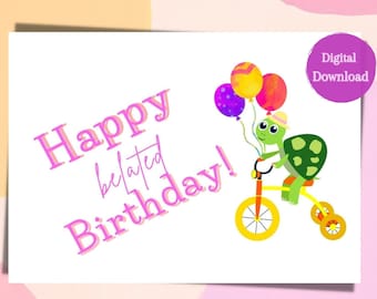 Op de afbeelding: Een roze en witte kaart met de tekst "Happy belated Birthday!" in roze. Een groene schildpad met een gele hoed rijdt op een gele driewieler met kleurrijke ballonnen.