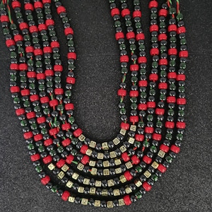 Puede incluir: Un collar de cuentas con cuentas rojas, negras y verdes. El collar tiene múltiples hilos, con cuentas doradas con letras que deletrean una palabra. Las cuentas están ensartadas en hilo verde y rojo.