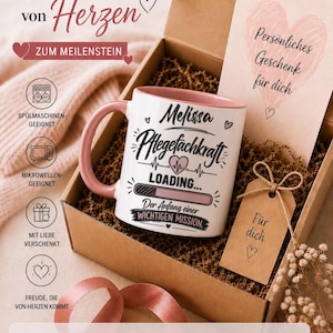 Könnte beinhalten: Ein weißer Keramikbecher mit rosa Henkel und Innenseite, bedruckt mit Melissa, Pflegefachkraft, LOADING und Der Anfang einer WICHTIGEN MISSION. Der Becher liegt in einer Kartonschachtel mit einer Karte mit der Aufschrift Persönliches Geschenk für dich.