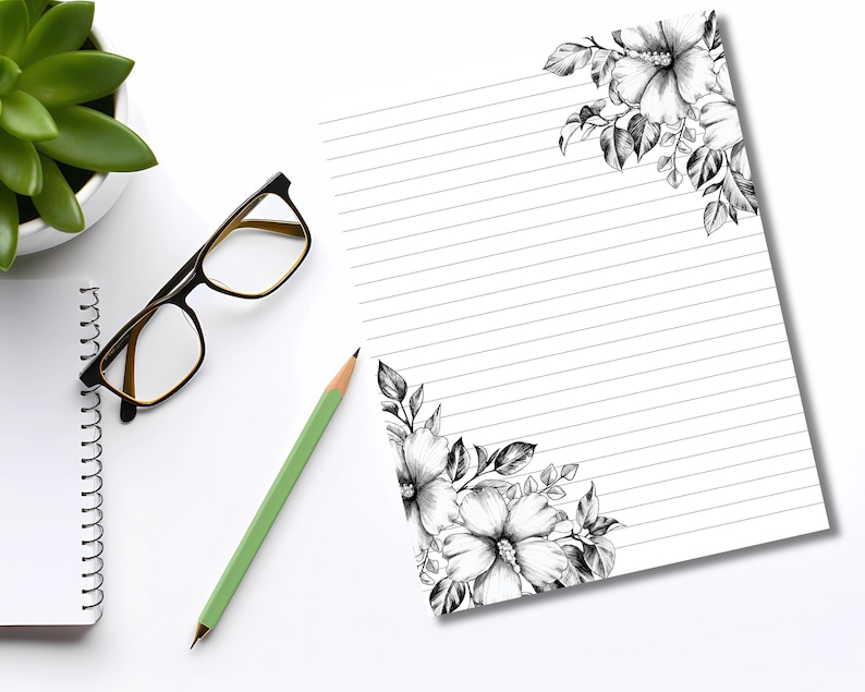 May include: A white notepad with horizontal lines and floral corner designs in black and white. A green pencil, black-framed glasses, and a small succulent plant in a white pot are also on the white surface.