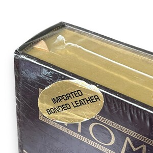 May include: Close-up of a dark brown box with gold accents and the text "TOM". A gold sticker reads "IMPORTED BONDED LEATHER". The box is wrapped in clear plastic.