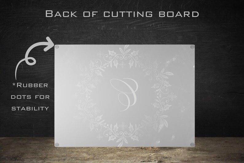May include: White glass cutting board with a white snowflake and floral design and a letter "C" in the center. The back of the board has rubber dots for stability.