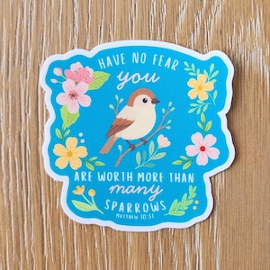 May include: A sticker with a blue background and a white border. It features a cartoon bird perched on a branch, surrounded by flowers. The text reads "Have no fear you are worth more than many sparrows" with a Bible verse reference.