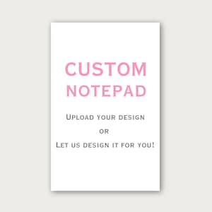 Pode incluir: Um bloco de notas retangular branco com o texto CUSTOM NOTEPAD em letras cor-de-rosa grandes. Abaixo, um texto cinzento mais pequeno diz UPLOAD YOUR DESIGN OR LET US DESIGN IT FOR YOU! O bloco de notas é apresentado num fundo claro e liso.