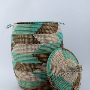 Puede incluir: Una cesta de almacenamiento tejida grande con tapa, que presenta un patr&oacute;n geom&eacute;trico en marr&oacute;n, blanco y turquesa.