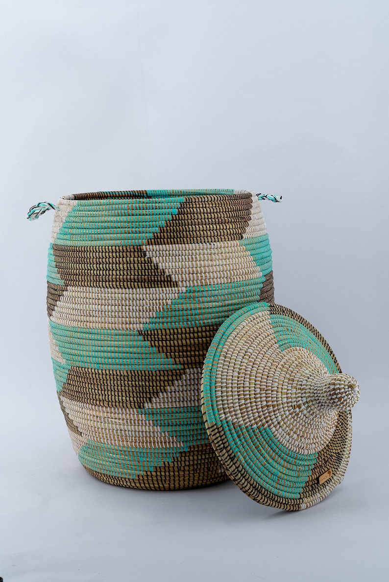 Puede incluir: Una cesta de almacenamiento tejida grande con tapa, que presenta un patr&oacute;n geom&eacute;trico en marr&oacute;n, blanco y turquesa.