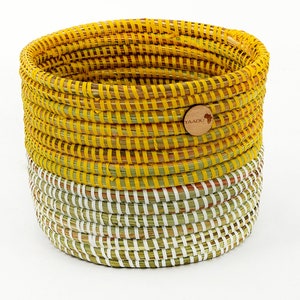 May include: A yellow and white woven basket with a wooden tag that says "YAADU" on it.