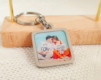 May include: A silver keychain with a square photo charm featuring a couple on a beach. The photo shows the couple sitting on a white pillow with the text "Mr. Right" and "Mrs. Always Right" written on their shirts.