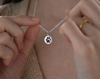 May include: A silver necklace with a small, round pendant featuring a paw print design.