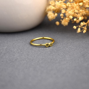 May include: A gold ring with two small circles, each with a letter, 'W' and 'S', engraved on them.