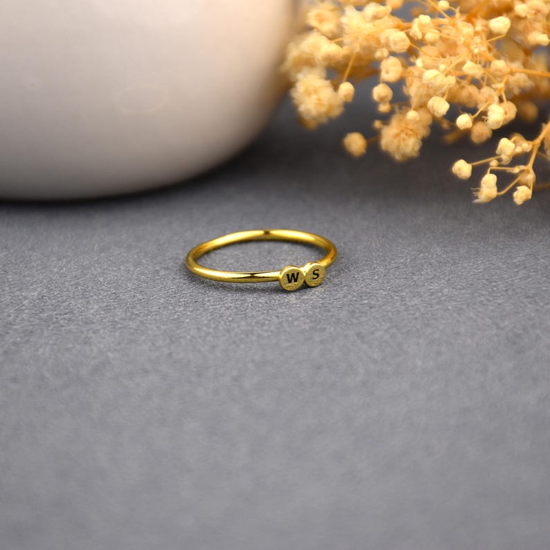 May include: A gold ring with two small circles, each with a letter, 'W' and 'S', engraved on them.