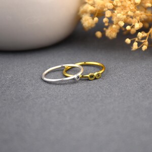 May include: Two thin silver rings with initial charms. The top ring has the letters "W", "S", and "A" on it. The bottom ring has the letter "A" on it.