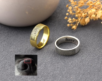 May include: Two rings, one gold and one silver, with textured surfaces. The gold ring has "Mott" engraved on it. The silver ring has "Bonnie" engraved. A small image of a dog's nose is in the lower left corner.