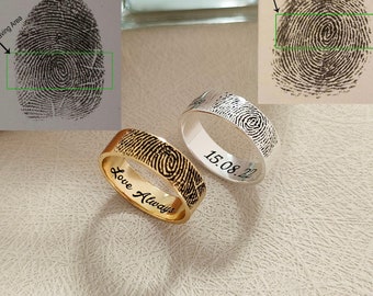 May include: Two rings featuring fingerprint patterns. One is gold-coloured with "Love Always" engraved, the other is silver-coloured with "15.08.22" engraved. The image also shows two fingerprint samples with an "Engraving Area" marked.