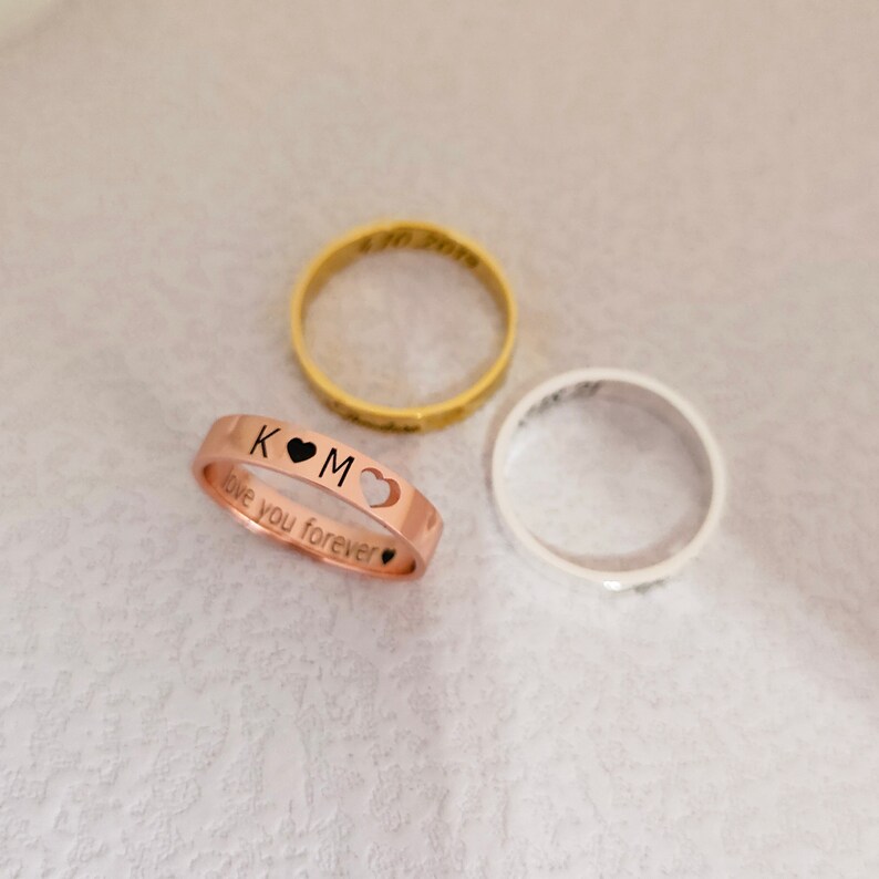 May include: Three rings, one gold, one silver, and one rose gold. The rose gold ring has the inscription "K &hearts; M love you forever" with a heart cut out of the band.