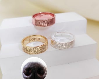 May include: Three personalized pet paw print rings in gold, silver, and rose gold. The rings are engraved with the names "Doris", "Bucc", and "Piper".