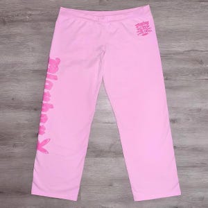Peut inclure: Pantalon de survêtement rose avec les mots "Playboy" et "Blackheart" imprimés dessus.